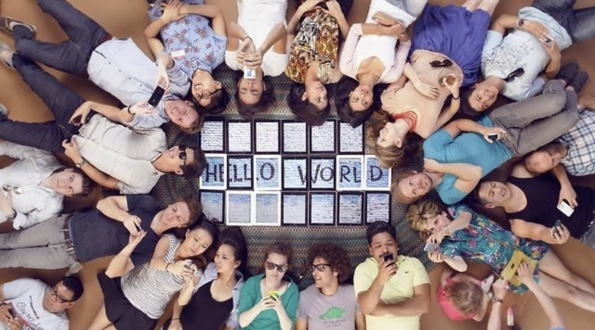 Overhead view of people around a grid of tablets spelling Hello World